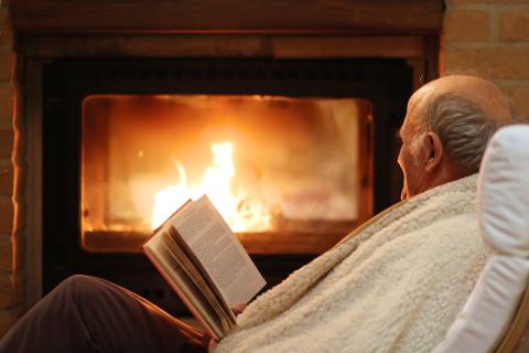 man reading book by fireplace